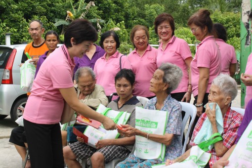团长郭秋贤分发红包给一位老妇人