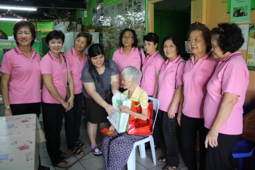 居士林执行秘书陈秋丽分发礼物于一位年长者。